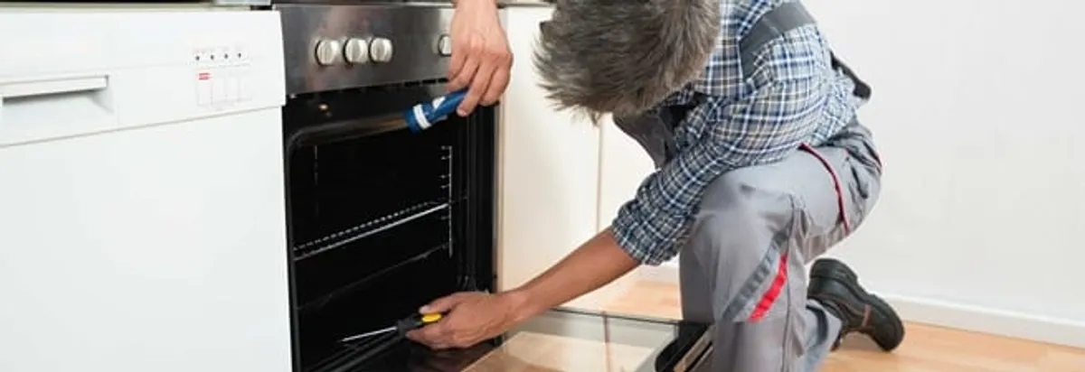 Oven repair technician inspecting and servicing an electric oven in El Paso, TX