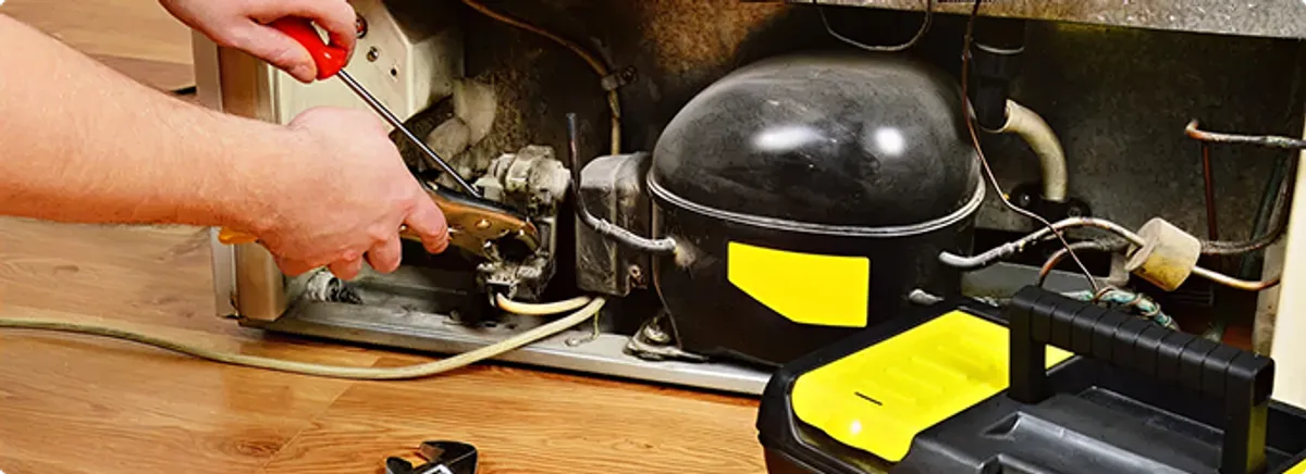 Refrigerator repair technician fixing the compressor and wiring in El Paso, TX