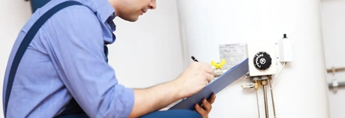Water heater repair technician inspecting the unit and recording service notes in El Paso, TX